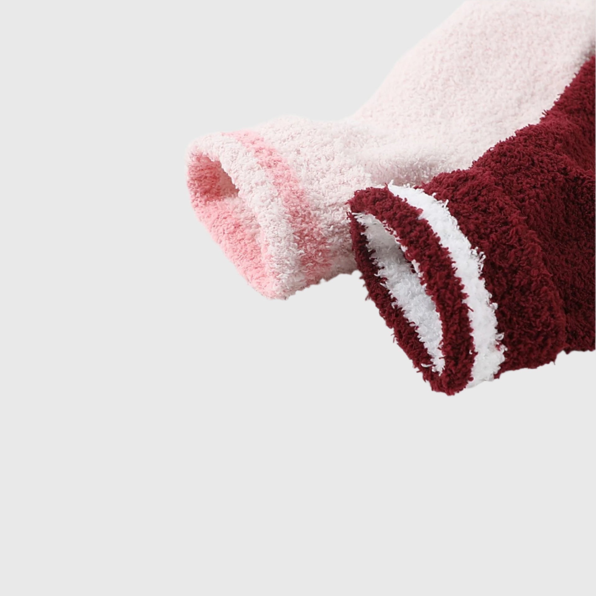 Close-up of pink and burgundy fluffy socks with white stripe detail, showing soft textured material