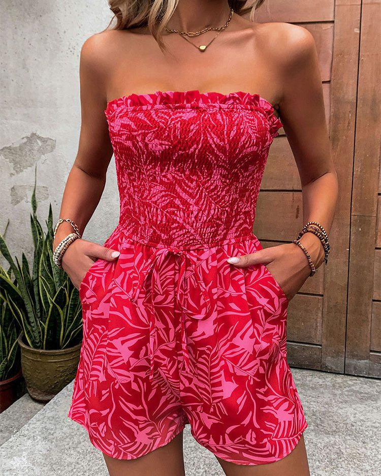 Front view of a woman in a red strapless smocked romper with a drawstring waist and pockets.