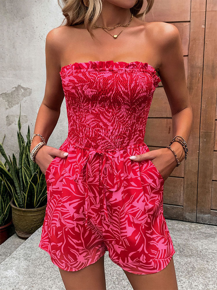 Front view of a woman in a red strapless smocked romper with a drawstring waist and pockets.