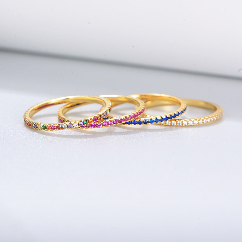 Side view of four gold stackable rings with multicolor, pink, blue and light blue stones showcasing prong settings