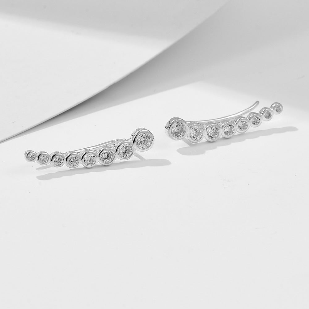 Silver ear climbers with crystal bezels photographed on white surface with shadow detail