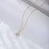 A gold Star of David pendant necklace with diamond-like crystals displayed on white fabric. The elegant six-pointed star hangs on a fine gold chain