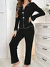 Black ribbed pajama set with white accent trim and bow closures, styled with pearl necklace, shown against white dresser and floral decor