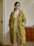 Olive green quilted puffer coat with toggle closures and hood, worn with cream turtleneck and pants