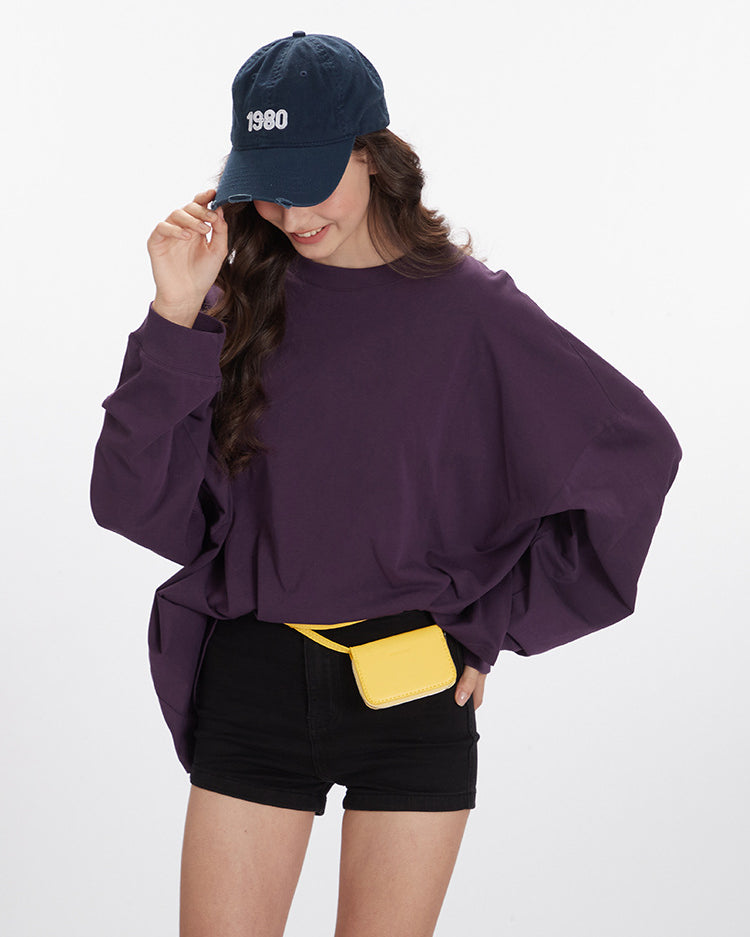 Casual styling of purple oversized sweatshirt with navy 1980 cap and yellow mini bag