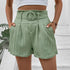 Front view of mint green high-waisted shorts featuring ruffled waistband with circular belt buckle and pleated design