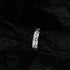 Artistic shot of silver engraved band ring against textured black background highlighting relief pattern