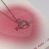 Silver heart pendant with arrow detail on pink gradient heart background, close-up view