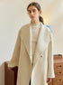 Close-up of cream wool coat's wide lapel and gold bar necklace styling