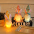  Three LED bunny gnome decorations in pastel colors, glowing warmly on a tabletop with books and decorative accents.