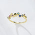 A gold bubble ring with multicolored gemstones arranged in scattered pattern photographed against clean white background