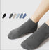 A model is wearing gray ankle socks against white backdrop. Inset shows color range of seven ankle sock options from black to navy in neutral tones