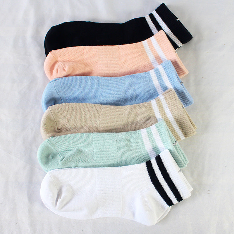 Flat lay of six different colored ankle socks with white stripes featuring blue, peach, black, beige, mint green, and white