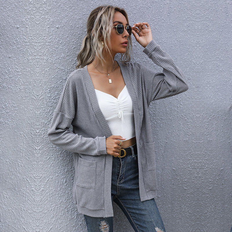 Stylish layered look with grey cardigan, white crop top, and designer belt