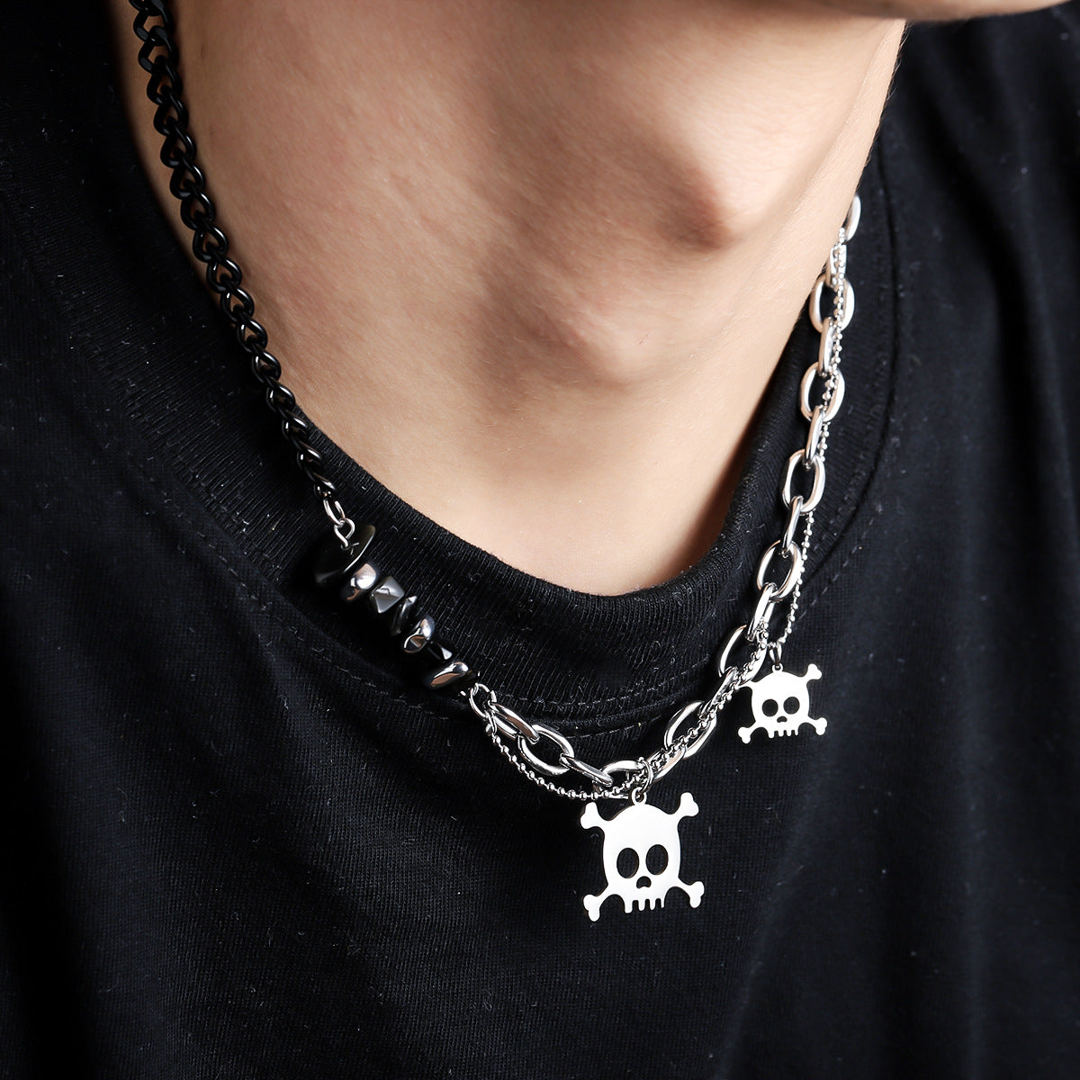 Titanium Steel asymmetric necklace featuring black chain with obsidian beads on one side, silver chain on other side, and white skull and crossbones charms, styled on model wearing black t-shirt
