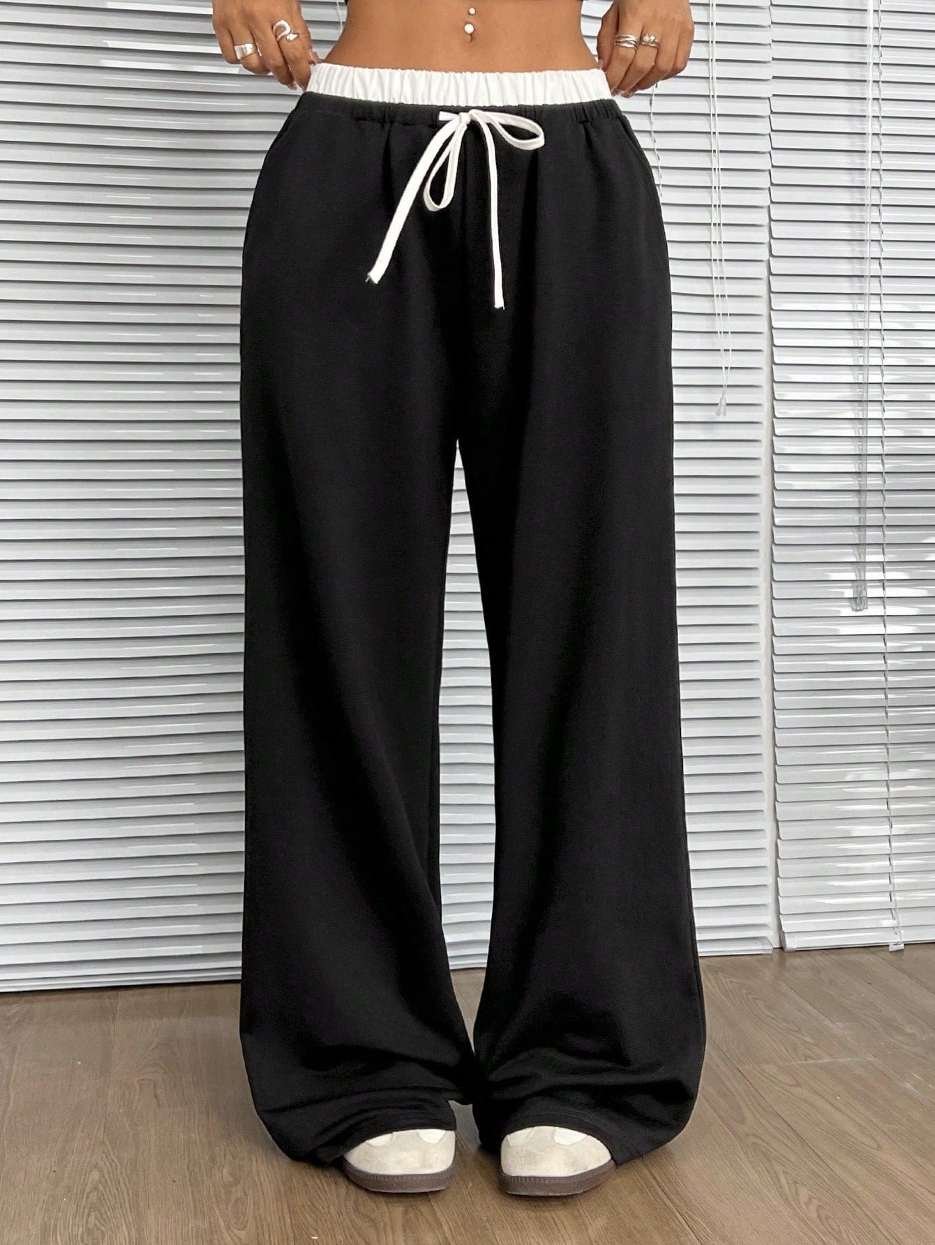 Front detail of black wide-leg pants with white drawstring and elastic waistband