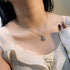 Delicate blue crystal square halo necklace styled with white ribbed top, elegant everyday jewelry lifestyle shot
