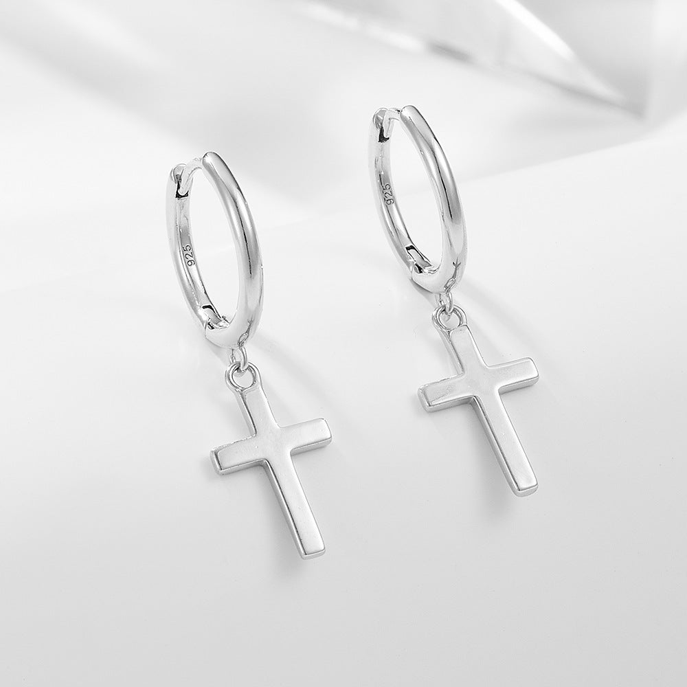 Silver huggie hoop earrings with cross charm pendants, showing '925' hallmark on minimalist white background with soft shadows