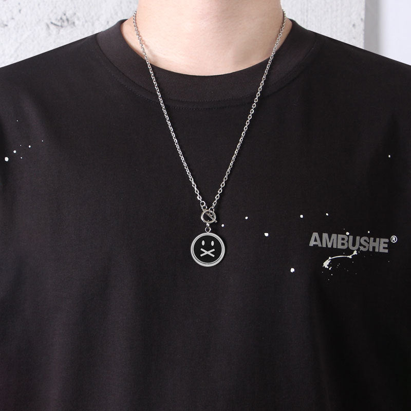 Titanium Steel chain necklace featuring sad face pendant against black Ambushe t-shirt with speckled design