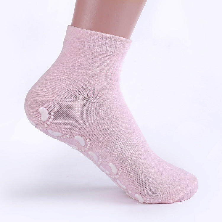 Close-up of pink ankle sock on mannequin foot showing white footprint pattern grip dots on sole against white background