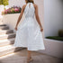 Back view of a woman in a white polka dot halter dress, showing an open-back detail with an elastic waist.