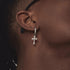 Zircon cross drop earring worn on dark skin, with black stud visible above