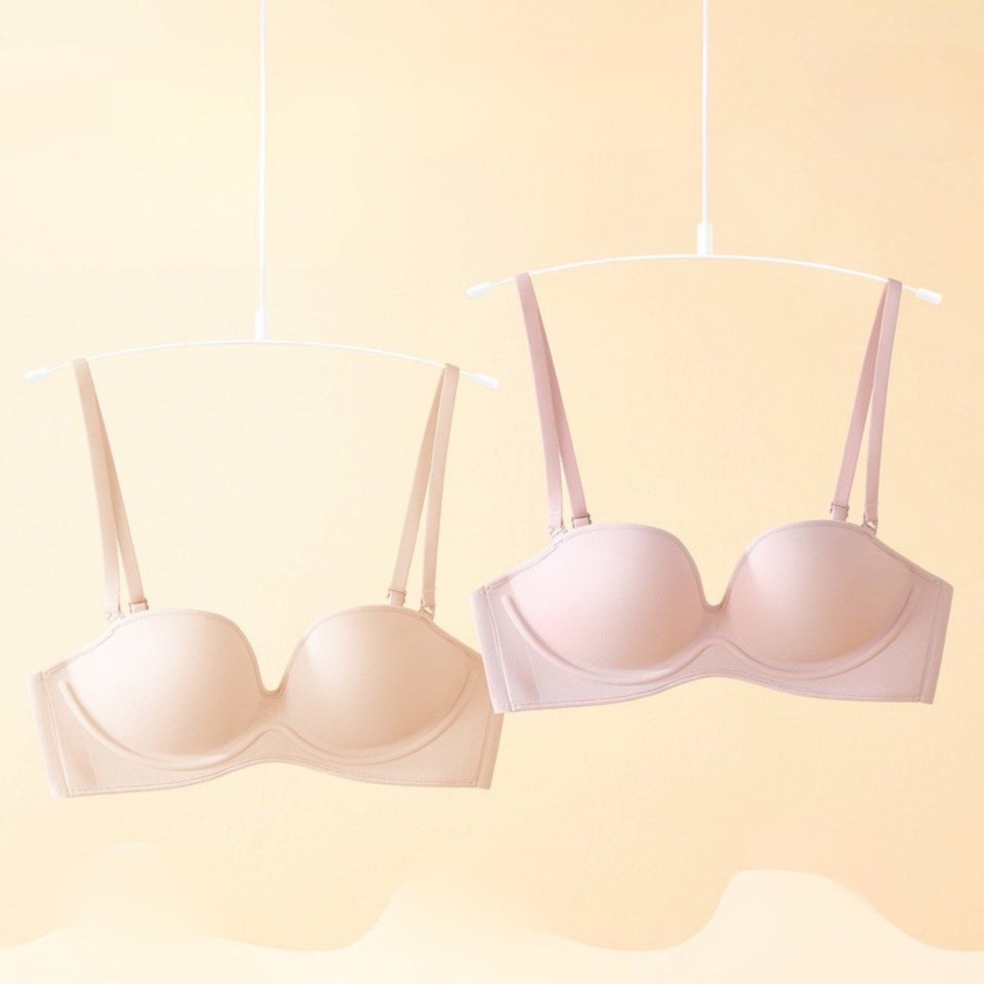 Two convertible bras in medium nude and pink hanging on a minimalist hanger, showcasing adjustable and removable straps for multiple styling options.