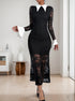 A woman in a black lace long-sleeve dress with a white pointed collar and flared cuffs, posing in a modern room with black heels.