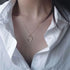 Silver crescent moon necklace worn with white collared shirt, showing delicate chain and pendant