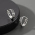 Sterling silver chain-style hoop earrings on black platform, close-up view.