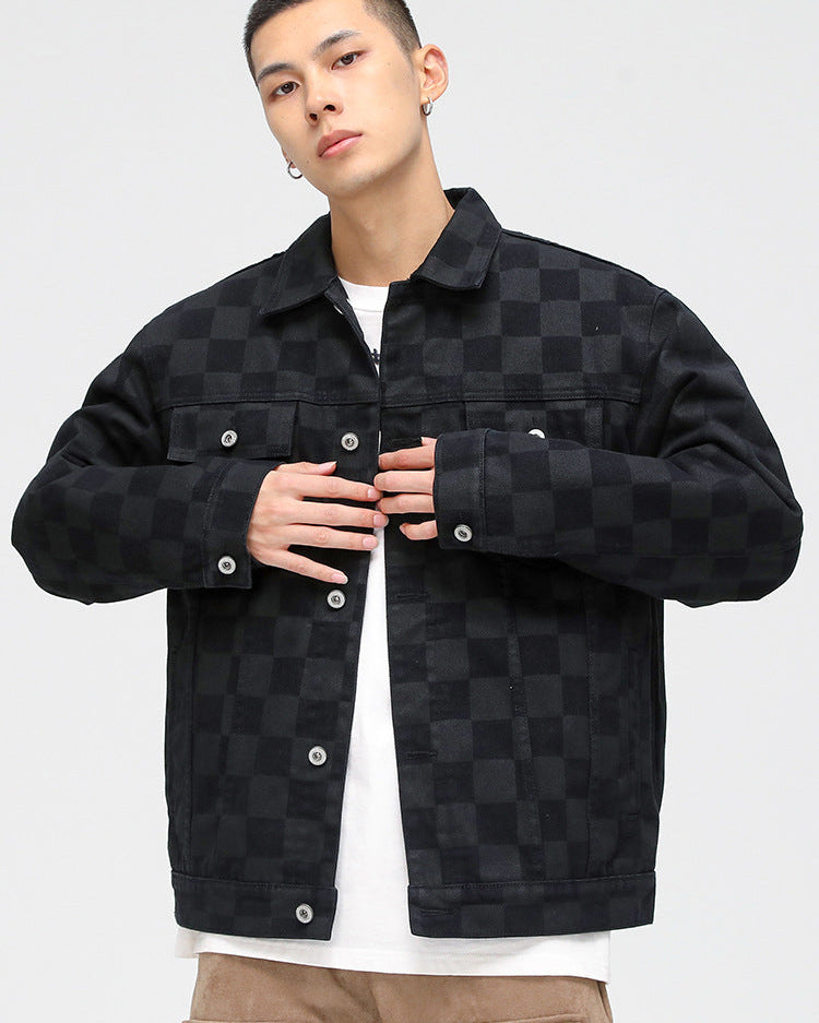A model is wearing a black checkered denim jacket over white t-shirt and tan pants, posing against white background