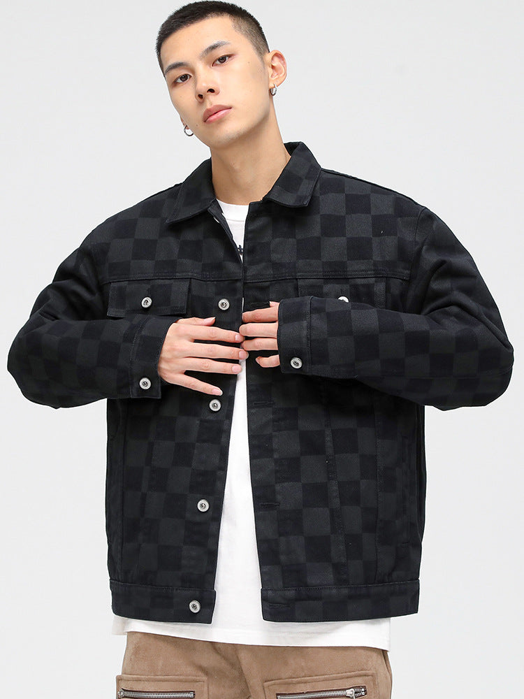 A model is wearing a black checkered denim jacket over white t-shirt and tan pants, posing against white background