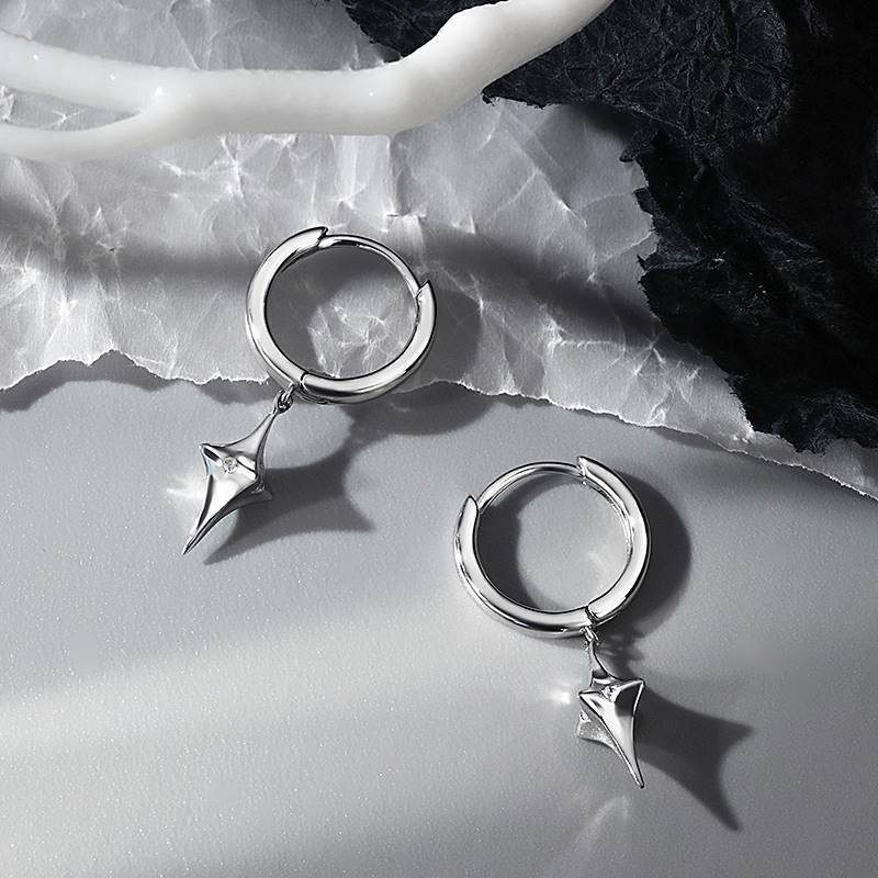 Silver star drop hoop earrings pair on textured white and black marble background