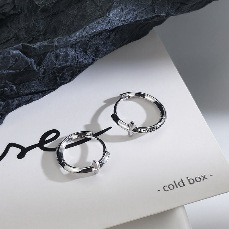 Silver star hoop earrings on white paper with dark stone background and 'cold box' word