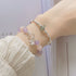 A woman wearing a pastel bead bracelet with silver bow charm and matching silver bangle on wrist against white sleeve background