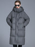 A woman wearing a gray quilted oversized puffer coat with high collar, black sunglasses and red lipstick, standing centered against gray background