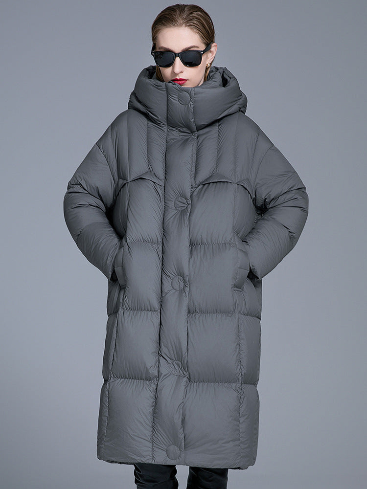 A woman wearing a gray quilted oversized puffer coat with high collar, black sunglasses and red lipstick, standing centered against gray background