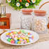Two transparent jar bags filled with white and golden-speckled eggs placed behind a plate of colorful speckled eggs on a table.