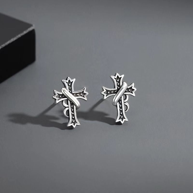 Silver stud earrings pair with vintage cross design and black antiqued details on gray background
