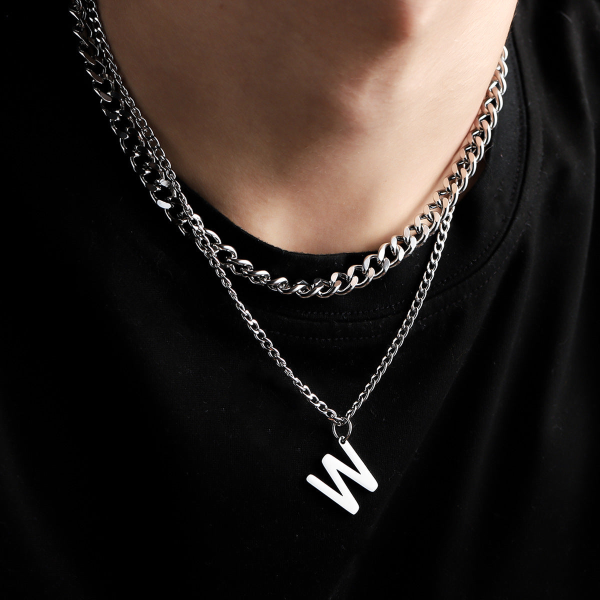 Layered silver chain necklace with W charm worn with black top