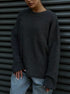 Close-up of charcoal grey chunky knit sweater with ribbed texture and relaxed fit, worn casually