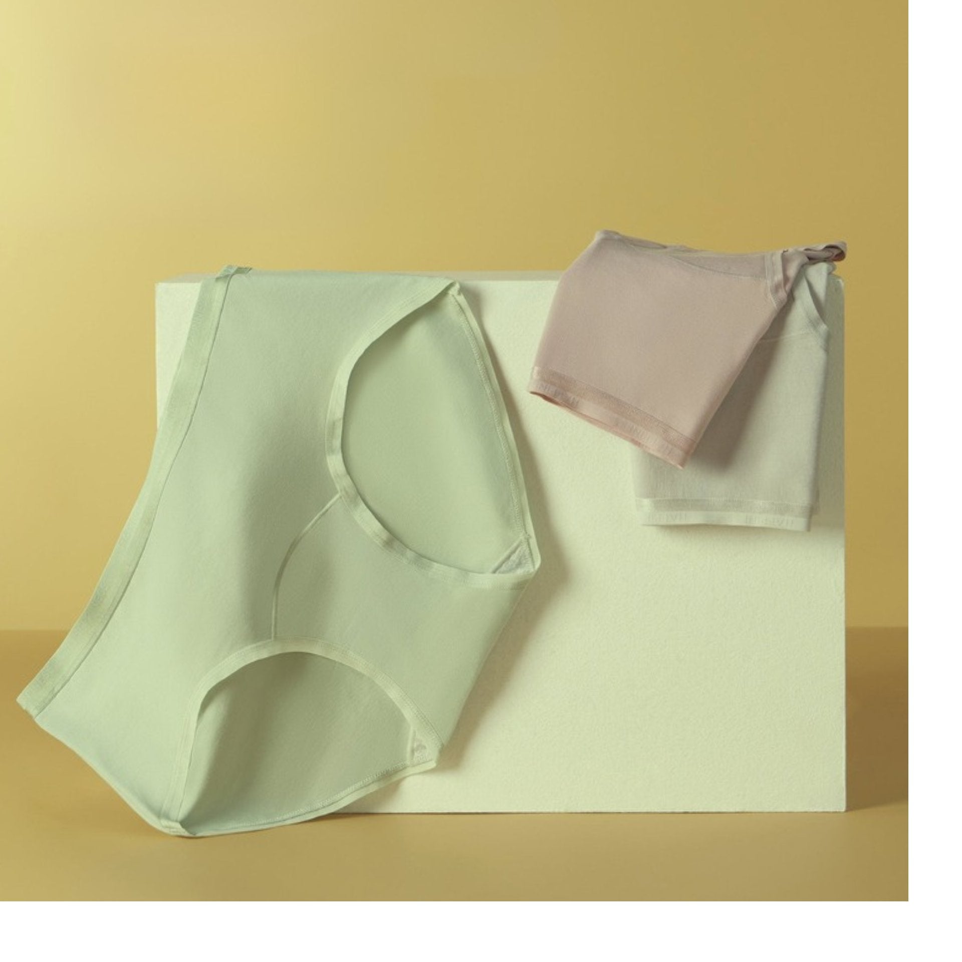 High-waisted briefs displayed on beige background - mint green and light pink colors