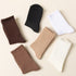 Four ribbed crew socks in brown, black, white, and beige arranged on a cream background showing full-length view