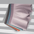Folded boxer briefs in multiple muted colors including gray, blue, and salmon, displayed on striped background
