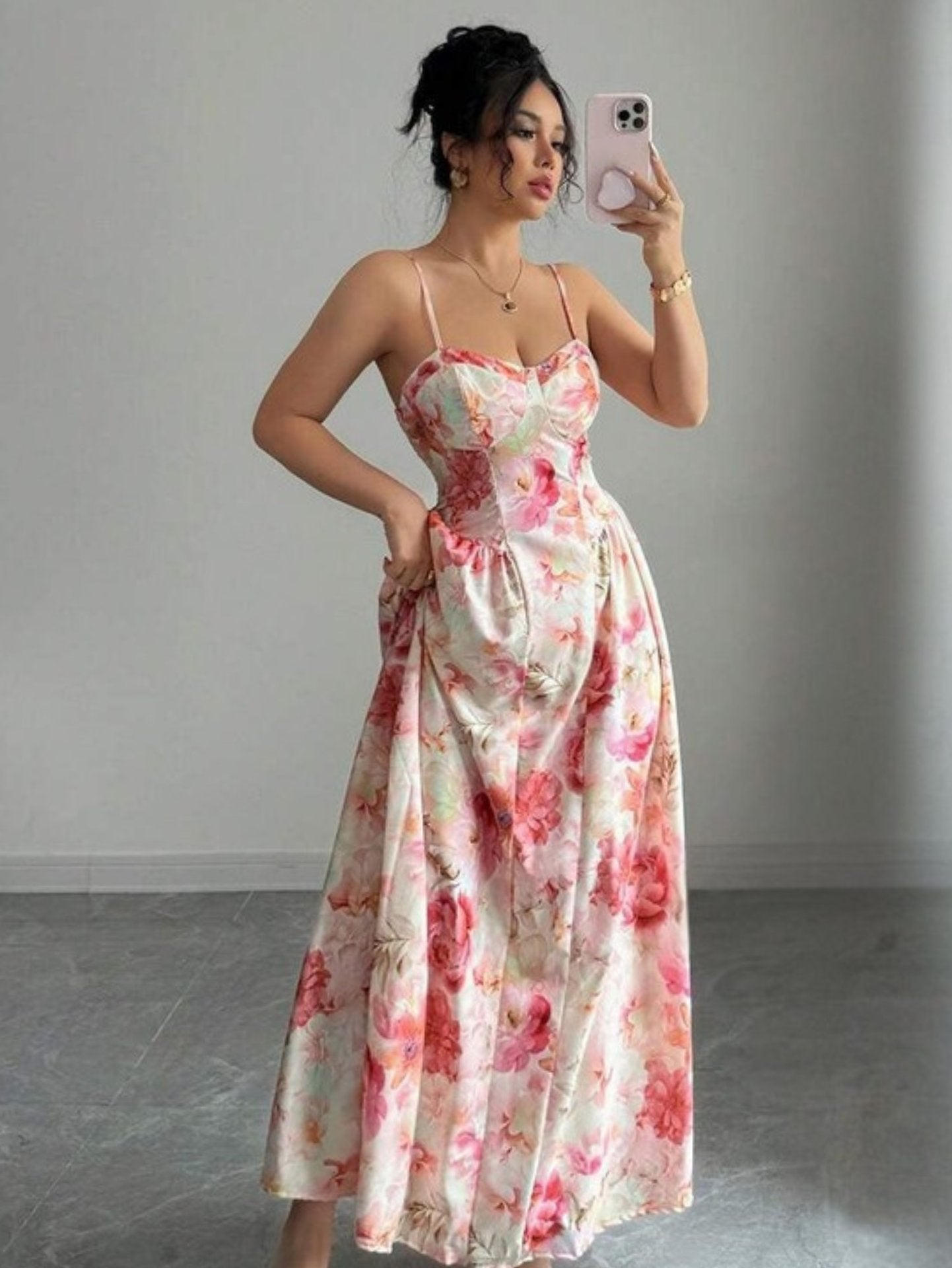 Woman taking a mirror selfie wearing a floral dress in a minimalistic setting.