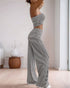 Side view of a woman in a black and white striped bandeau top and wide-leg pants, posing with her hands raised, showing the outfit’s fit.
