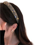 Woman wearing a black rhinestone headband, styled with pearl earrings and a black velvet outfit,