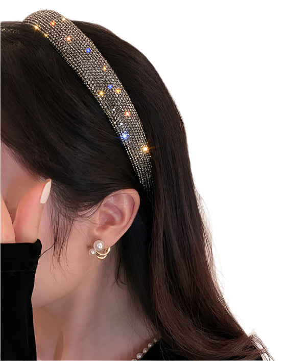 Woman wearing a black rhinestone headband, styled with pearl earrings and a black velvet outfit,