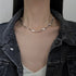Woman wearing a silver sculpted chain necklace with an organic, wavy design, paired with a denim jacket