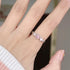A person with white sleeve showing silver ring with pink heart gemstone and diamond accents on finger, with manicured nail visible